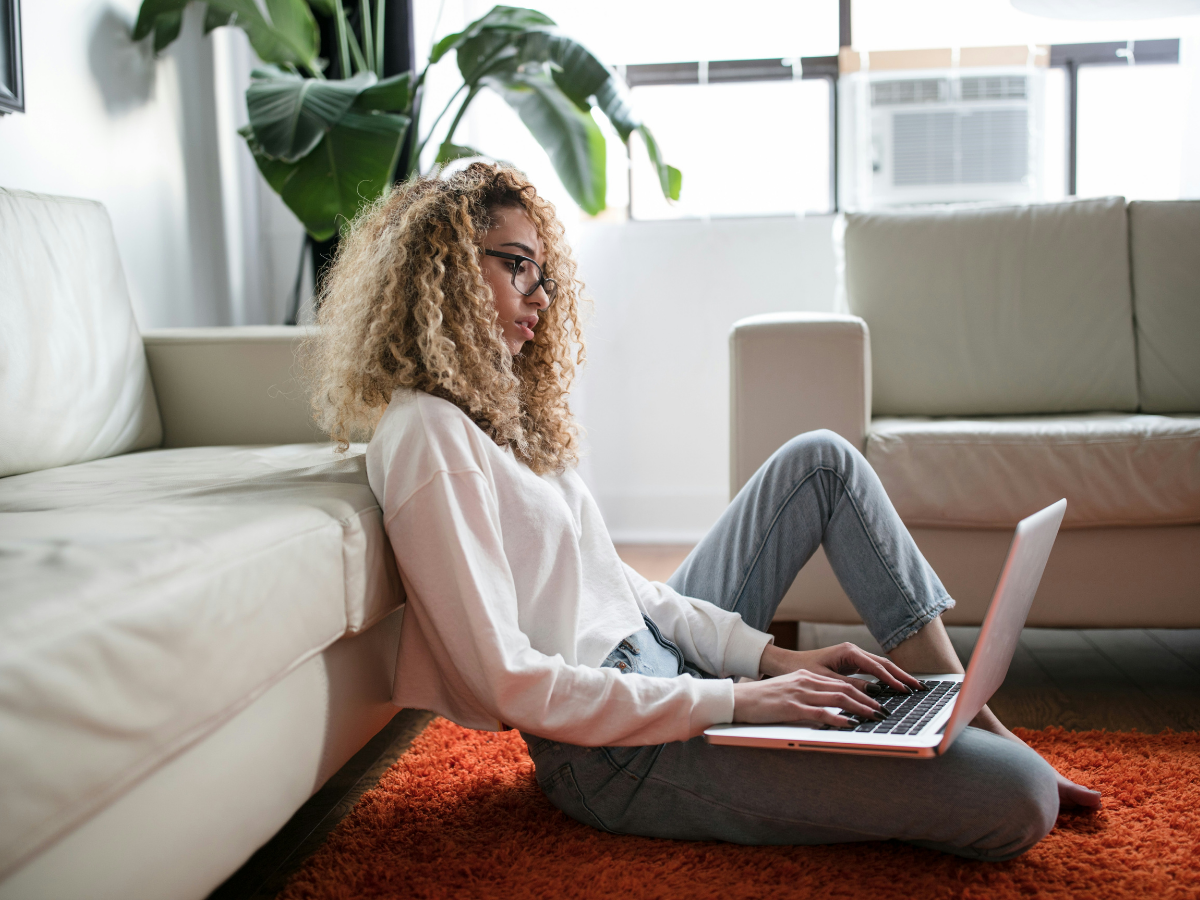 Girl sitting at lap top on the floor, presumably setting up her website